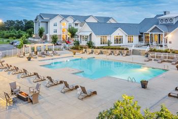 a swimming pool with chairs around it and a building in the background